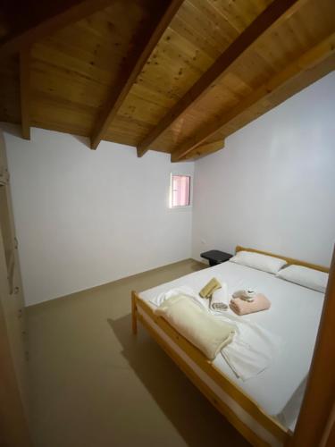 a bedroom with a white bed with a wooden ceiling at L.T. Apartment 5th street in Sarandë