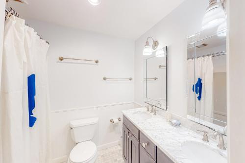 La salle de bains blanche est pourvue de toilettes et d'un lavabo. dans l'établissement Pine Cottage, à Seal Harbor