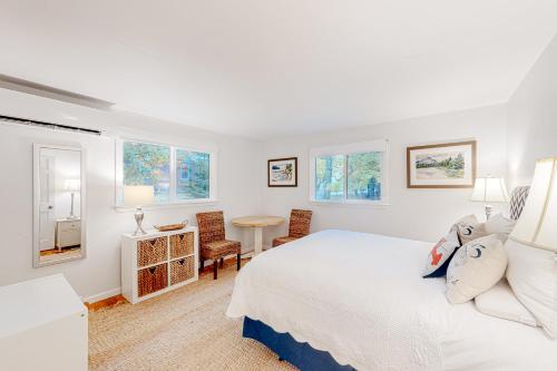 a white bedroom with a bed and a table at Pine Cottage in Seal Harbor
