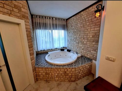 a bathroom with a large tub in a brick wall at The Pearl of the Golan - Pnina BaGolan in Had Nes