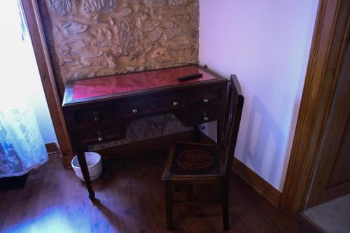 a wooden desk with a chair next to a wall at O Pombal in Alcanena