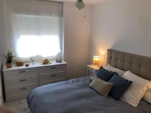 een slaapkamer met een bed, een raam en een dressoir bij Sanlúcar Playa de las Piletas in Sanlúcar de Barrameda