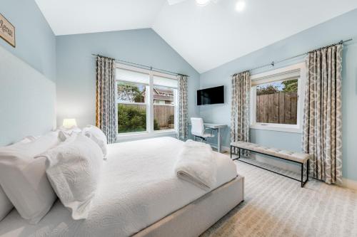 a bedroom with a large white bed and windows at Seaside Ocean Getaway in Seaside