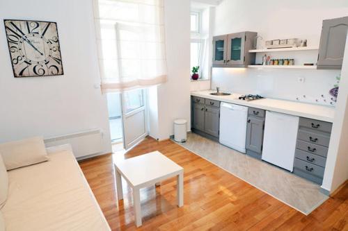 Charming Apartment في زغرب: مطبخ مع دواليب بيضاء وطاولة في الغرفة