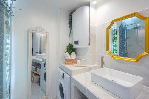 une salle de bain blanche avec un lavabo et un miroir dans l'établissement Au pied de Notre Dame de la Garde, à Marseille