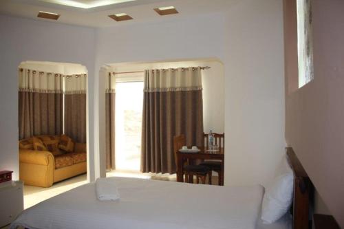 a bedroom with a bed and a window with a couch at Jebel Shams Resort منتجع جبل شمس in Dār Sawdāʼ