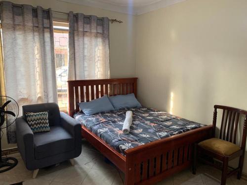 una camera da letto con un letto, una sedia e una finestra di Vine suites a Kampala