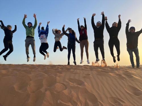 a group of people jumping in the desert at Merzouga Luxury Tents - Glamping in Merzouga