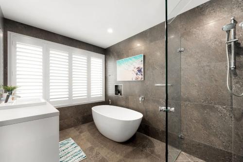 y baño con ducha de cristal y bañera blanca. en Exclusive Executive waterfront home, en Mooloolaba