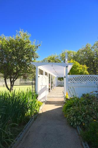 a white pergola with a white fence and a sidewalk at The Lodge at Jackson Village in Jackson