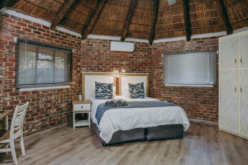 1 dormitorio con 1 cama en una pared de ladrillo en Cosy Cottages Guesthouse, en Potchefstroom