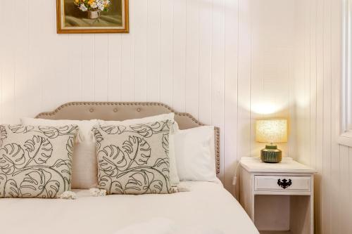 a bed with white pillows and a lamp on a table at Unwind at Secret Garden Maleny 3 BR Family Home in Maleny