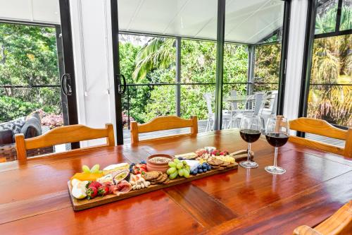 a tray of food and two glasses of wine on a table at Unwind at Secret Garden Maleny 3 BR Family Home in Maleny