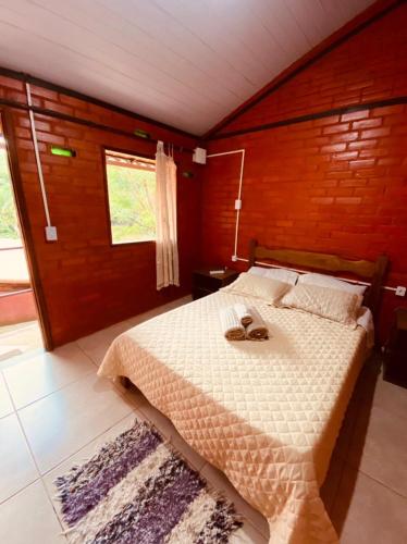 a bedroom with a bed with two shoes on it at Pousada, Camping e Restaurante do Sô Ito in Santa Rita de Jacutinga