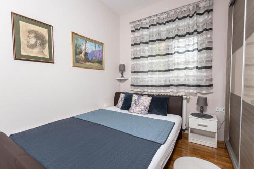 een slaapkamer met een bed en een groot raam bij Apartman Gundulić in Vinkovci