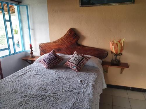 a bedroom with a bed with pillows on it at Finca Jardín del Agua in Sasaima