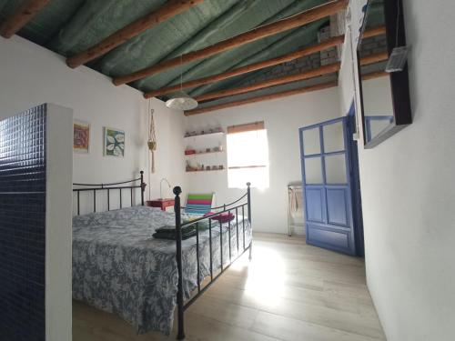 um quarto com uma cama e uma porta azul em El Charcón em Higuera de la Sierra