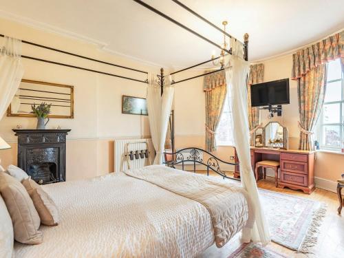 Edderton Hall Country House في Forden: غرفة نوم مع سرير المظلة ومكتب