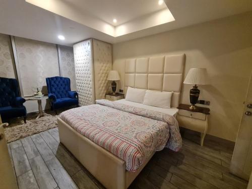 a bedroom with a large bed and a blue chair at Royal Residencia Centaurus in Islamabad