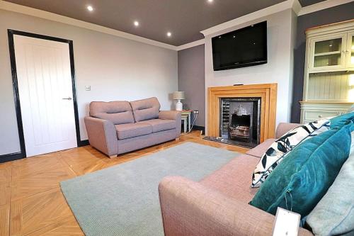 a living room with a couch and a chair and a television at Honeybee Cottage in Lincolnshire