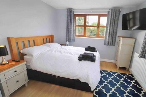 a bedroom with a white bed and a window at Honeybee Cottage in Lincolnshire