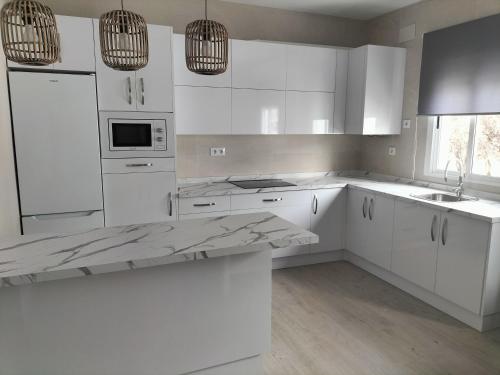 uma cozinha branca com armários brancos e um lavatório em Apartamento zafra Cristina em Zafra
