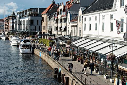a group of people walking on a sidewalk next to a river at Moderne leilighet midt i sentrum av Fredrikstad in Fredrikstad