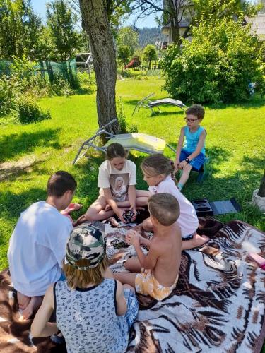 a group of children sitting on a blanket in the grass at Agroturystyka Pod Modrzewiem in Zubrzyca Górna