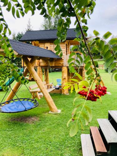 a wooden cabin with a swing and a gazebo at Agroturystyka Pod Modrzewiem in Zubrzyca Górna