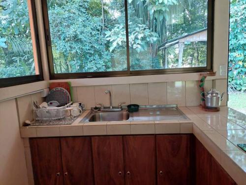 cocina con fregadero y 2 ventanas grandes en Casa a 26 kilómetros de Jaco rodeado de naturaleza, en Jacó