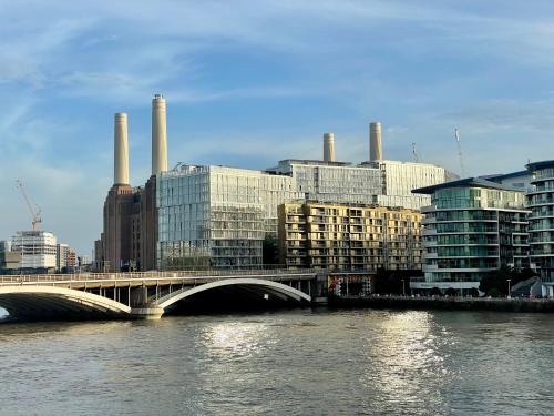 a bridge over a river with buildings and a city at Battersea Power Station Living in London