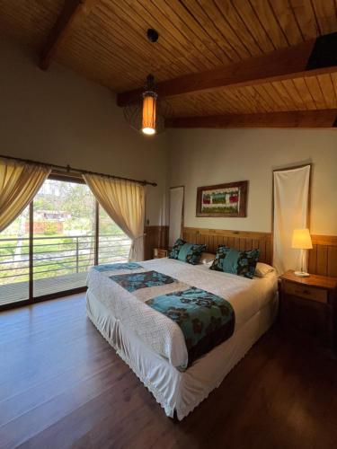 a bedroom with a large bed and a large window at Cabañas Alto Bosque in Pucón