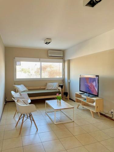 sala de estar con sofá y TV en APART CIUDAD MENDOZA en Mendoza