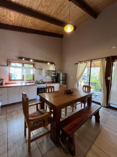 a kitchen and dining room with a wooden table and chairs at Cabañas Alto Bosque in Pucón