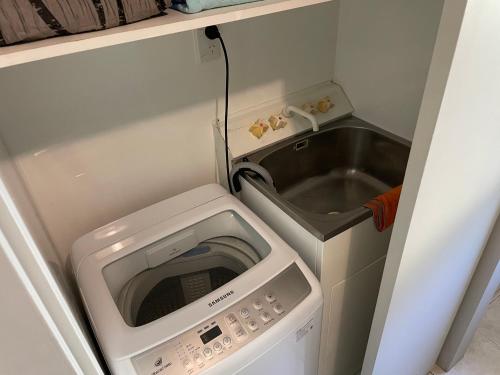 a small kitchen with a microwave and a sink at Ohope Beach Dreamer in Ohope Beach