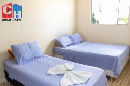 two beds in a room with blue sheets at Cizah Hotel in Faxinal