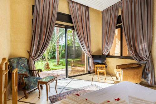 a bedroom with a bed and a chair and windows at Villa près de golfs in Marrakech