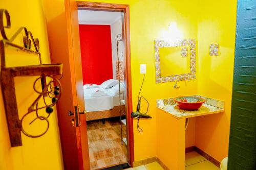 Baño amarillo con lavabo y espejo en Pousada Kabana de Pedra, en Ibicoara