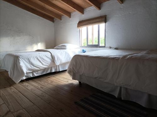 um quarto com 2 camas e uma janela em Casa Vapahí em Barra de Valizas