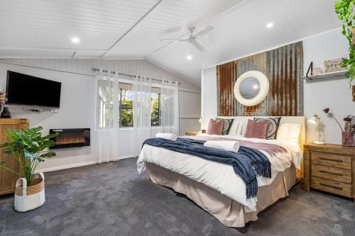 a bedroom with a large bed and a flat screen tv at Tamborine Palms Farmhouse in Tamborine