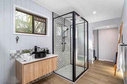 a bathroom with a glass shower and a sink at Tamborine Palms Farmhouse in Tamborine