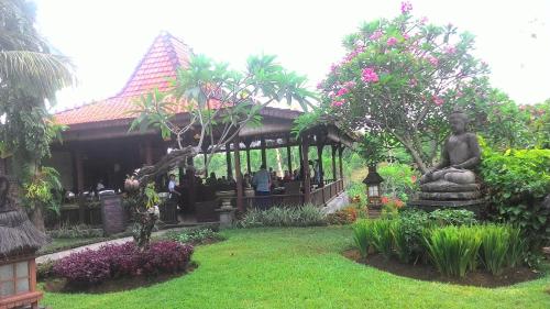 a garden with a statue in front of a building at Shanti Natural Panorama View Hotel in Singaraja