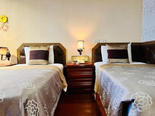 una camera con due letti e un comodino con due lampade di Shinyes Motel a Su-ao