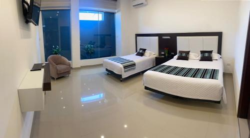 um quarto com duas camas e uma cadeira. em HOTEL INNOVA em Tarija