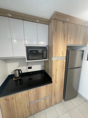a kitchen with white cabinets and a stainless steel refrigerator at Departamento completo Surquillo/Miraflores in Lima