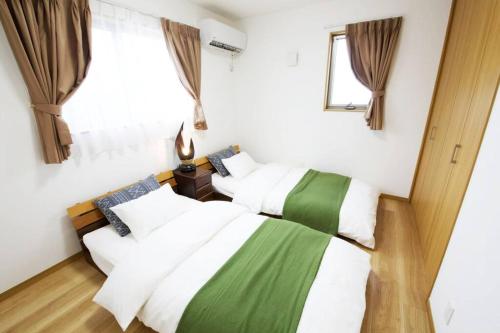 two beds in a room with white and green at Bunzo Rezort 今帰仁 in Shushi