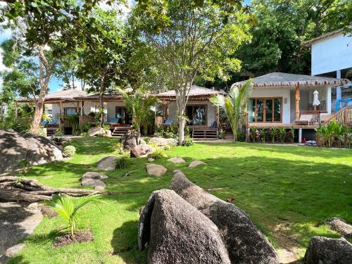 a house with rocks in front of a yard at Siam Cookies Cottage in Haad Pleayleam