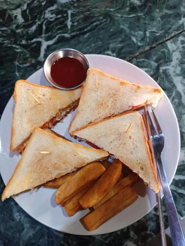 a white plate with a sandwich and french fries at Crocodile Safari Camp in Chitwan