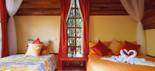 a bedroom with two beds and two swan pillows at Jardin entre Montañas in Bijagua