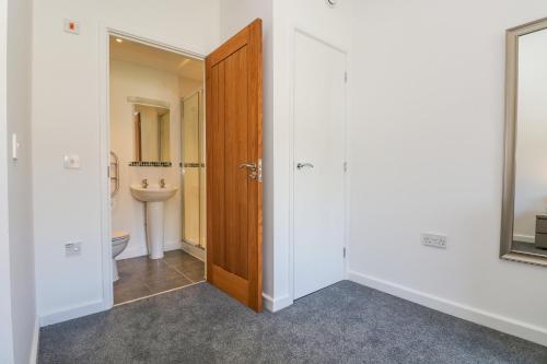 a bathroom with a toilet and a wooden door at Sea Breeze 17 Gannel in Truro